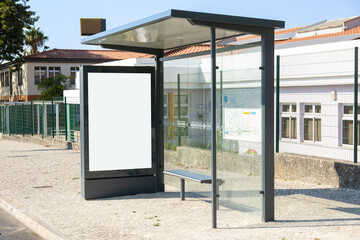 Modern bus stop with empty advertising billboard and glass shelter on a sunny day.