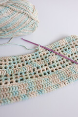 Obraz premium Ball of yarn with crochet hook and handmade fabric in pastel colors