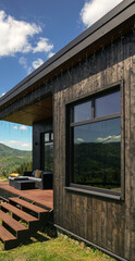 Big window of black wooden house with mountain view