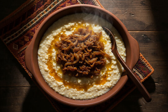 Eye-Level Shot of Creamy Jareesh with Ghee and Onions in Traditional Clay Pot &ndash; Bedouin Style