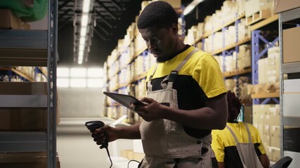 Black staff member using a barcode scanner to process shipping labels on boxes from shelving units. Scanning awb tags for package tracking service with tracking info, accurate logistics. Camera A.