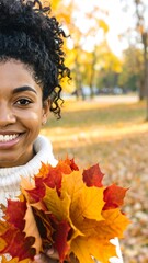 A joyful woman holds a bouquet of vibrant autumn leaves, her smile reflecting the season's beauty.