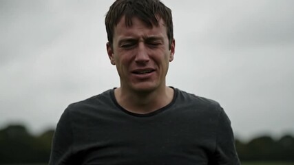 Man in distress with hands on head outdoors against an overcast sky and blurred green background