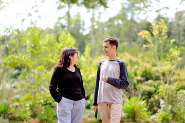 Happy adult son and mother talking and laughing together outdoors, enjoying a warm moment of...