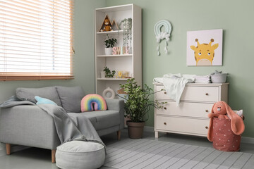 Interior of nursery with commode, shelf unit and sofa