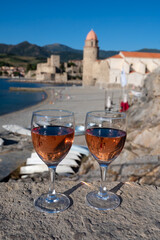 Glasses of rose Collioure AOC wine in sunlights with view on old town Collioure, colorful houses, church, castle and beaches, Occitanie, France, tourists destination