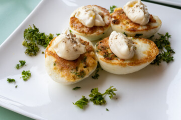 French high cuisine starter dish, pan fried chicken eggs with special filling and yellow sauce, vegetarian food in French restaurant