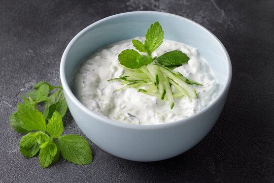 Fresh traditional Greek tzatziki sauce with yogurt, cucumber and mint light blue ceramic bowl on dark background. Healthy Mediterranean appetizer, dip or dressing