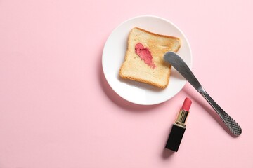 Toast with lipstick and butter knife on light pink background, flat lay. Space for text