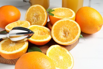 Squeezer, oranges and mint on white table, closeup. Making fresh juice