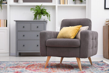 Grey armchair with pillows indoors. Interior design