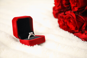 Dreams come true. Beautiful engagement ring in box and flowers on light plaid, closeup