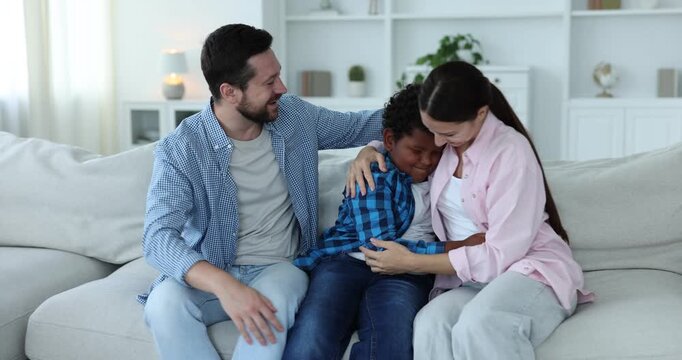Adoption. Happy parents and their son having fun together at home, camera moving right - Powered by Adobe