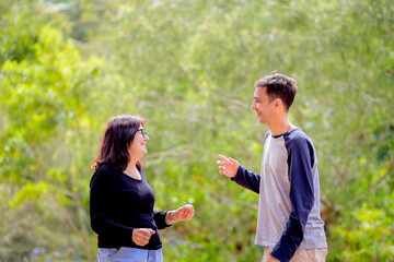 Happy adult son and mother talking and laughing together outdoors, enjoying a warm moment of...
