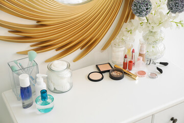 Set of cosmetic products and vase with flowers on table, closeup