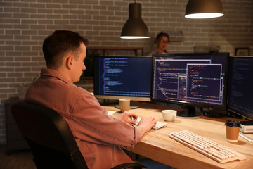 Male programmer working with computer in office at night