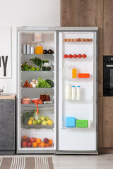 Open big fridge with fresh products in kitchen