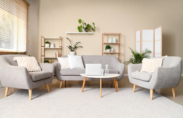 Interior of living room with sofa, armchairs and aroma spray on table