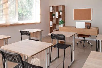 Interior of light classroom with  desks and chairs at school