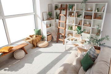 Interior of living room with shelving unit with books, ladder and sofa