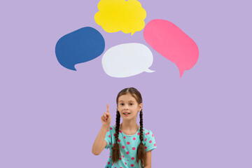 Cute little girl pointing at blank speech bubbles on lilac background