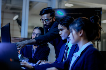 A diverse team of Asian and Indian AI developers collaborates on complex code. A senior engineer...