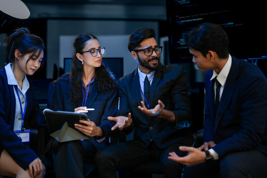 A diverse team of AI strategists in a project huddle, reviewing a neural network design on a tablet. A concept for agile development, collaborative problem-solving, and tech innovation.