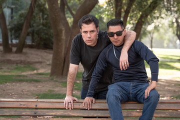 Two men posing together outdoors, with one arm around the other.