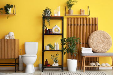Interior of restroom with toilet bowl, commode and bench
