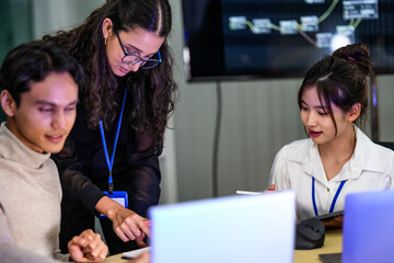 A diverse group of professionals in a corporate workshop on AI development. A female instructor supervises as the team learns to code advanced machine learning models on their laptops.