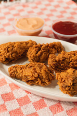 Close-up view of fried chicken with different sauces on a table with a tablecloth.