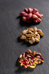 Raw pistachios on granite surface. Fresh pistachio Nuts on grey stone. Pile of pistachios on grey granite. Natural pistachios on stone texture.