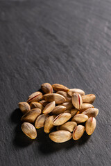 Raw pistachios on granite surface. Fresh pistachio Nuts on grey stone. Pile of pistachios on grey granite. Natural pistachios on stone texture.