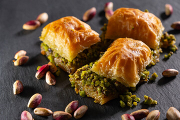 Traditional pistachio baklava on granite. Close-up of pistachio baklava on granite background. Turkish dessert baklava with pistachios. Pistachio baklava on stone surface.