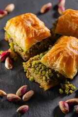 Traditional pistachio baklava on granite. Close-up of pistachio baklava on granite background. Turkish dessert baklava with pistachios. Pistachio baklava on stone surface.