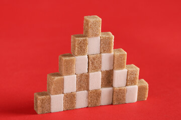 Heap of many different sugar cubes on red background