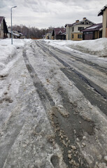 Spring thaw. Snow-covered, uncleared road in a siberian cottage village.
