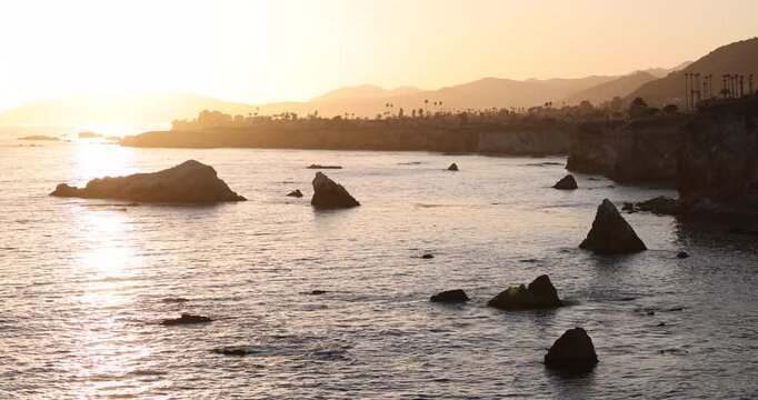 Sunset waves crash along the rugged coast of Pismo Beach, California, USA.