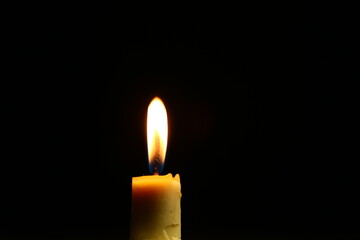 Closeup burning candle on dark black background, candle fire flame light with empty space. Ritual with romantic candle wax fire