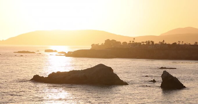 Sunset waves crash along the rugged coast of Pismo Beach, California, USA.
