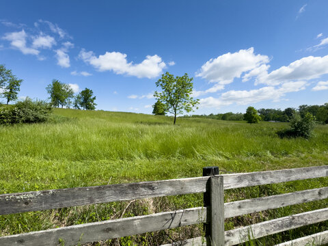 Rural midwestern landscape of a cleared field with fence and blue sky