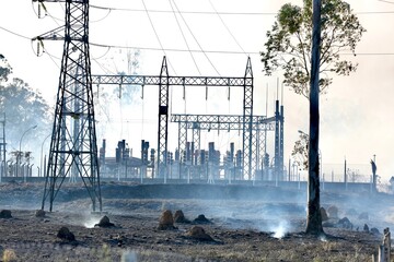 Linha de transmissão elétrica no meio da fumaça após incêndio em área de vegetação....