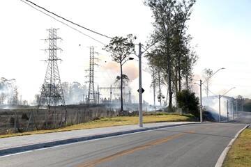 Linha de transmissão elétrica no meio da fumaça após incêndio em área de vegetação. Conceito de energia, meio ambiente, impacto ambiental, alterações climáticas e infraestrutura.