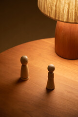 wooden table lamp on the table. A pair of puppets sit on a wooden table. Under a mushroom lamp, they stare at each other. An emotional scene.