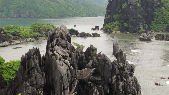 Drone view of jagged limestone cliffs rising above calm waters in Hienghene, New Caledonia iconic Poule rock formation.