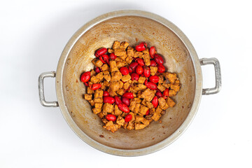 Top down cooking of stir-fried sweet tempeh mixed with melinjo skin in a frying pan isolated on a white background
