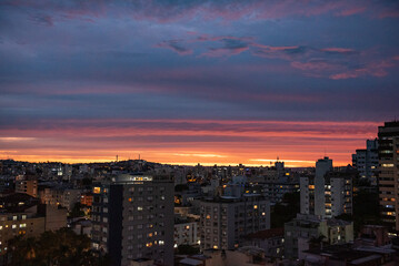Cityscape at sunset with dramatic colorful sky and urban skyline illuminated by evening lights