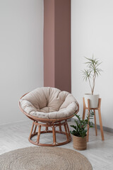 Comfortable armchair and houseplants near white wall in room