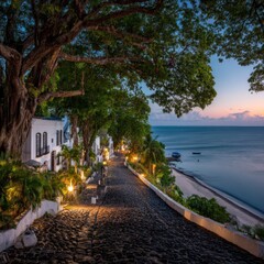 Naklejka premium A cobblestone path winds down to a tranquil beach at twilight, lined with white colonial buildings and lush tropical foliage.