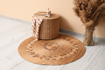 Vase with pampas grass and wicker basket on carpet near beige wall in room